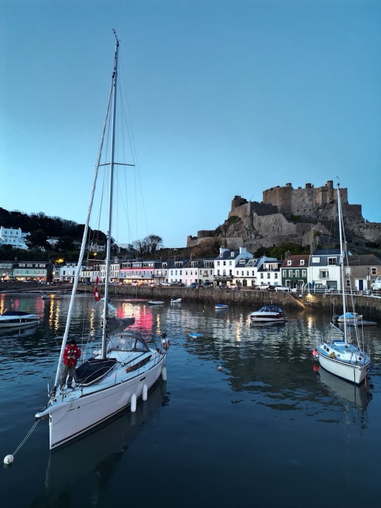 Segelyacht im Hafen von Gorey auf Jersey in der Abenddämmerung, darüber die Burg Mont Orgueil