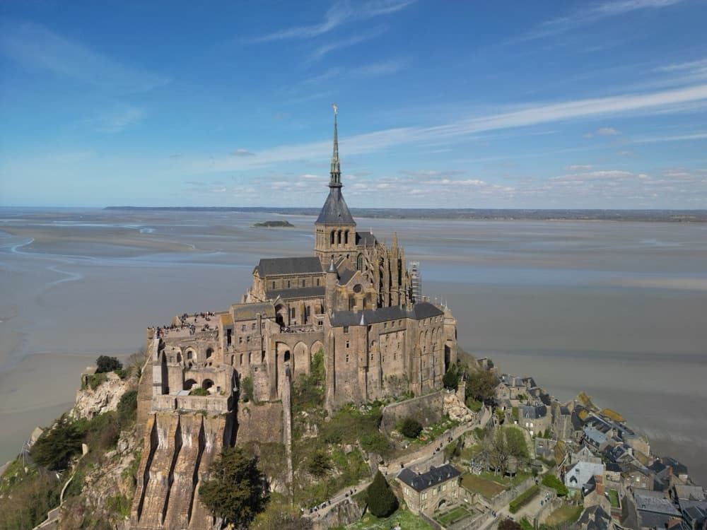 Der Mont-Saint-Michel aus der Luft, umgeben von weiten Sandflächen bei Ebbe
